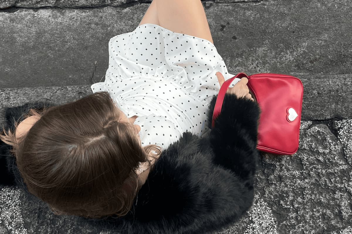 girl sitting with polka dot dress and red bag
